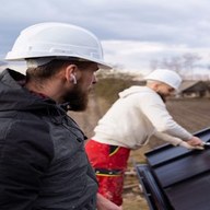 Two roofers checking seams on a steel roof